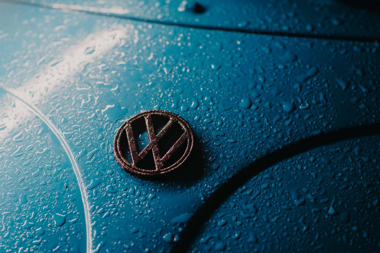 Detailed shot of a car hood with water droplets, showing texture and color contrast.